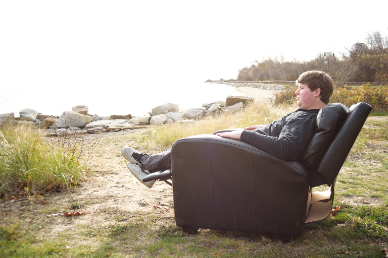 Comedian, Colby Bradshaw, in an armchair by the ocean.