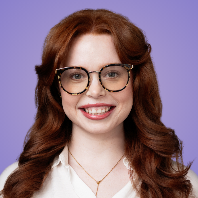 Headshot of woman with red hair and glasses with background color changed to purple so it is on brand.